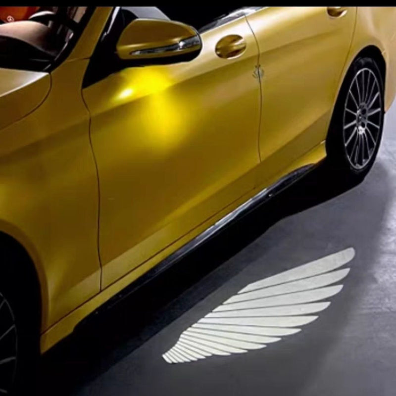 Car Rearview Mirror Angel Wings Lamp projection light illuminating angel wings on a yellow car surface.